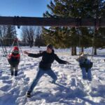 Mat pushing both Isaac and Iden on the swings, practicing for his second child on the way!