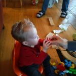 teaching Isaac to blow on the mouth piece of his new musical instrument