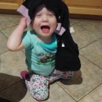 trying to put on her sweater